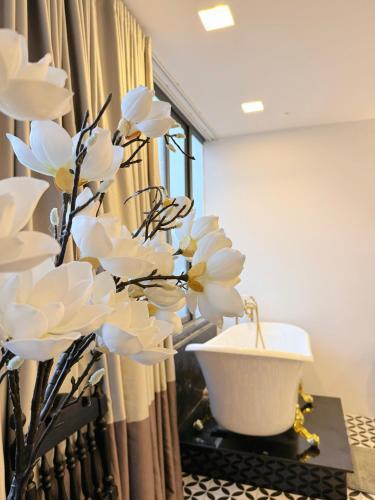 a bathroom with a tub and white flowers on a table at TTR Skypool View Hotel in Da Lat