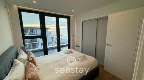 a bedroom with a bed and a large window at Sail Penthouse - Beach & Parking in Kent