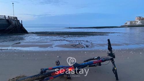 a bike parked on the beach next to the water at Sail Penthouse - Beach & Parking in Kent