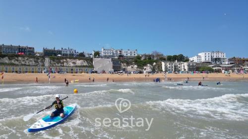 a man riding a paddle board in the water at a beach at Sail Penthouse - Beach & Parking in Kent