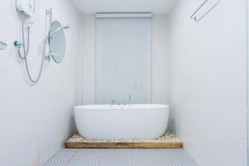 a white bathroom with a tub and a shower at Varni Homestay in Phatthalung