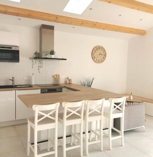 une cuisine avec une table et quatre tabourets blancs dans l'établissement Le cottage patio, à Ferrières