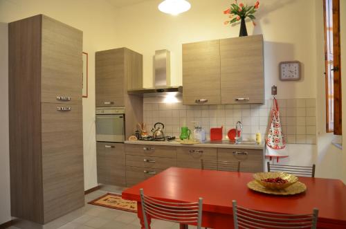 a kitchen with a red table and a kitchen with cabinets at Donnaberarda in Cortona