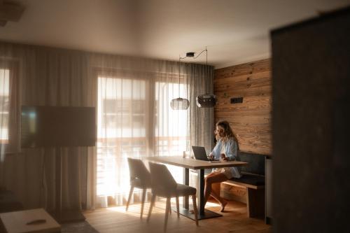a woman sitting at a table with a laptop at Chalet Lumis in San Vigilio Di Marebbe