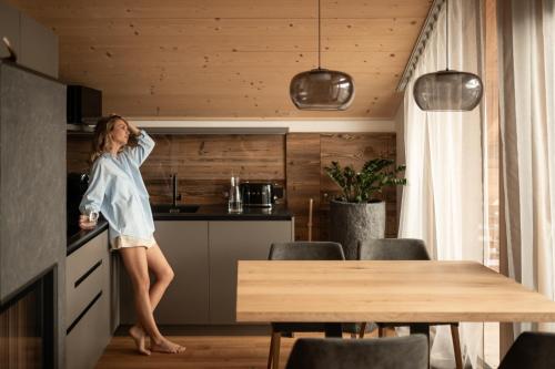a woman standing in a kitchen with a table at Chalet Lumis in San Vigilio Di Marebbe