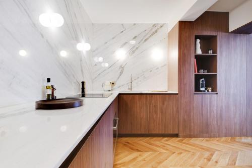 une cuisine avec un comptoir blanc et des placards en bois dans l'établissement ONIRI - Serviced Apartment in Saint Germain, à Paris