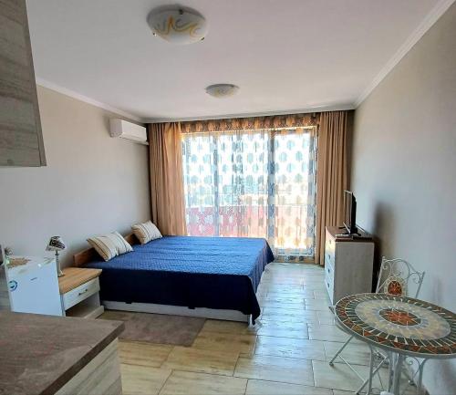 a bedroom with a blue bed and a large window at Admiral Plaza 35 -studio-Sunny Beach in Sunny Beach