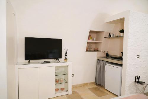 a living room with a flat screen tv on a white cabinet at La Chianca Rosa - RIFUGIO ROMANTICO ad Ostuni in Ostuni