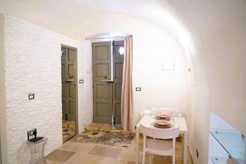 a white table and chairs in a room with a door at La Chianca Rosa - RIFUGIO ROMANTICO ad Ostuni in Ostuni