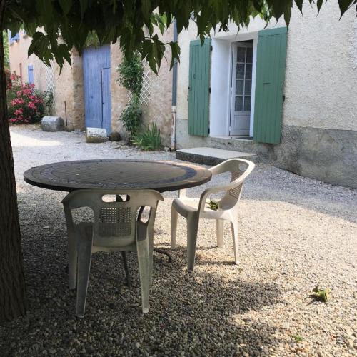 une table et deux chaises assises sous un arbre dans l'établissement Mas du Prescondu, à Mirabel-aux-Baronnies