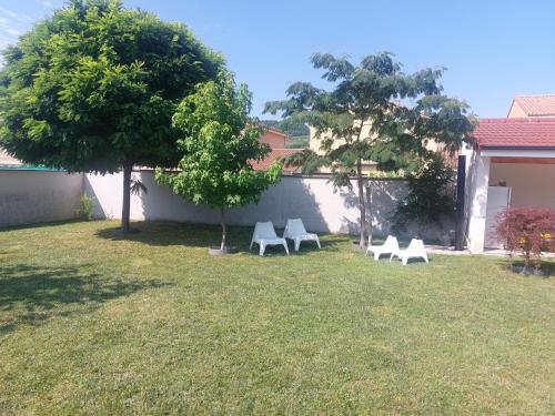 3 chaises blanches dans une cour avec un arbre dans l'établissement jolie maison dans un quartier calme, à Saint-Vallier