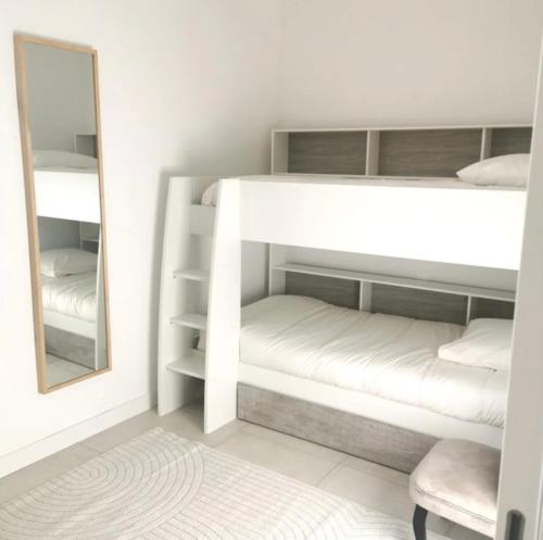 - une chambre avec des lits superposés, un miroir et une chaise dans l'établissement Le cottage patio, à Ferrières