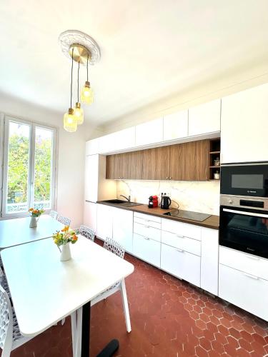 une cuisine avec des armoires blanches et une table blanche dans l'établissement Villa Lila Nice, à Nice