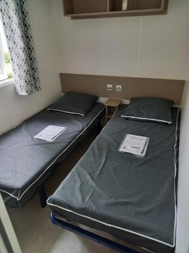- 2 lits dans une petite pièce avec des papiers dans l'établissement Mobil Home Vias plage La Carabasse terrasse fermée hors saison, à Vias