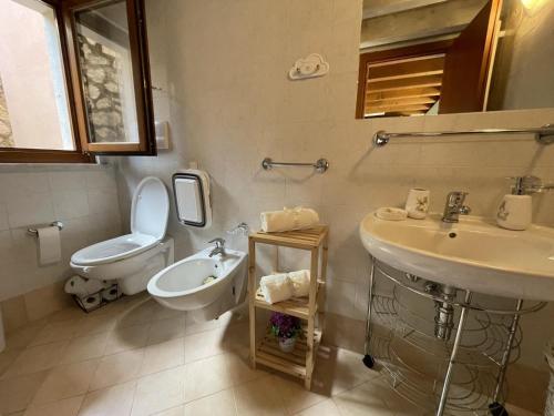 un baño con inodoro y lavabo en schönes Ferienhäuschen in ruhiger Lage für max. 4 Personen mit Pool, en Olzano
