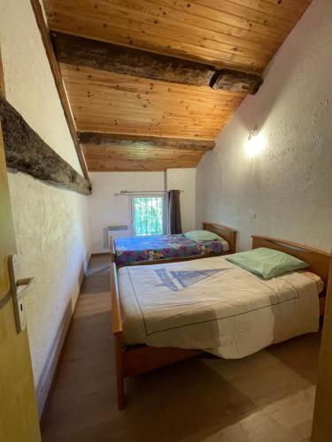 Mont-RocGite LA LICORNE的小型客房设有两张带木制天花板的床。