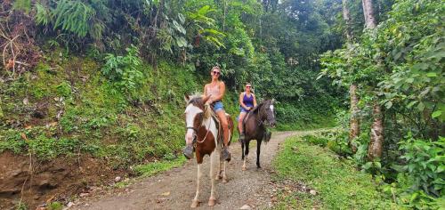 two people riding horses down a dirt road at Hotel Rivel - Restaurant & Nature Retreat in Turrialba
