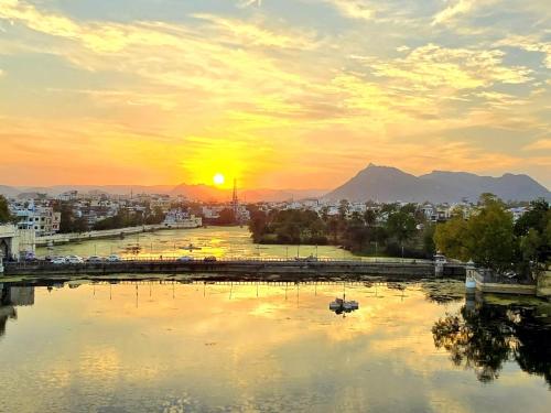 a view of a city with the sun setting over a river at Antariksh in Udaipur