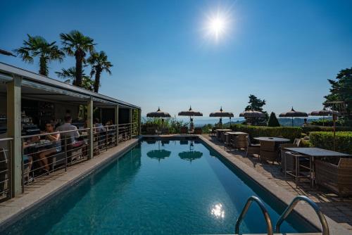 a pool at a resort with tables and umbrellas at Villa Sassolini Suite & Rooms - Country Boutique Hotel in Montevarchi