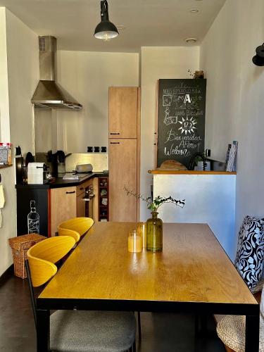 une cuisine avec une table en bois et des chaises jaunes dans l'établissement Trésors de la Cathédrale, Maison de Ville sur 4 niveaux, à Narbonne
