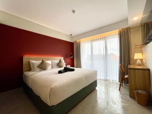 a bedroom with a large bed with a red wall at Anaya Hotel Canggu in Canggu
