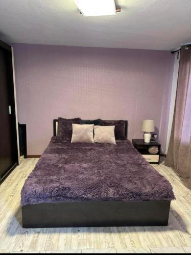 a bedroom with a large bed with a purple wall at Вила Николета in Sveti Vlas
