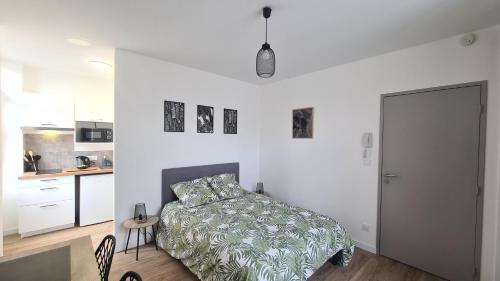 une chambre blanche avec un lit et une cuisine dans l'établissement Studio Ludo 1, parking privé, wifi, climatisation, entrée autonome, à Poitiers