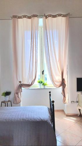 a bedroom with a bed and a window with curtains at POMPEI VESEVUS APARTAMENT in Boscotrecase