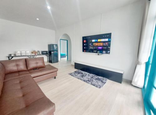a living room with a couch and a flat screen tv at พูลวิลล่าบางแสน 3ห้องนอน 4ห้องน้ำ in Ban Laem Thaen