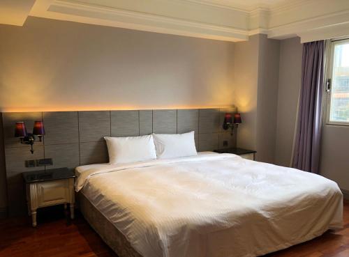 a bedroom with a large white bed and two lamps at 麗隆商旅LilongHotel in Kaohsiung