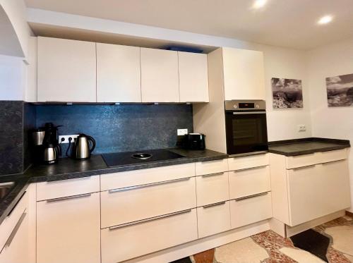 a kitchen with white cabinets and black counter tops at Ferienwohnungen Angerer Kederlehen in Berchtesgaden