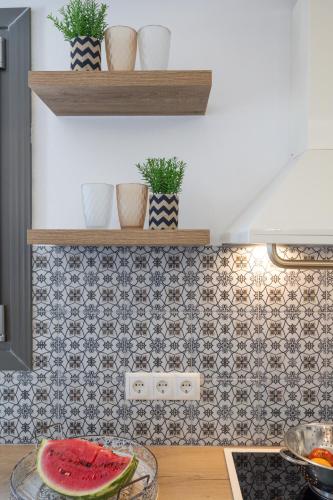 a kitchen with a tile wall and shelves with plants at BLUE SEA Naxos in Stelida