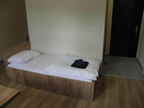 a bed with white sheets and a blue book on it at Anieli Krzywoń in Szczecin