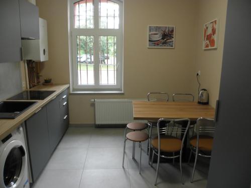 a kitchen with a table and chairs and a table and a window at Anieli Krzywoń in Szczecin