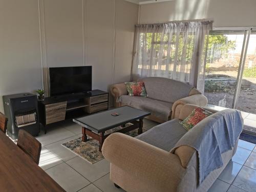 a living room with two couches and a flat screen tv at Die Windpomp in Vanderkloof