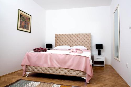 a bedroom with a large bed with a pink blanket at Apartman Suncokret Šabac in Šabac