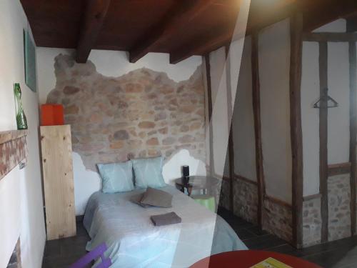 una camera da letto con un letto e un muro di pietra di Odyssée a Vallon-en-Sully