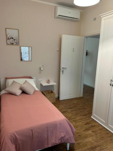 a bedroom with a bed with a pink blanket at Mavi Rooms in San Gavino Monreale