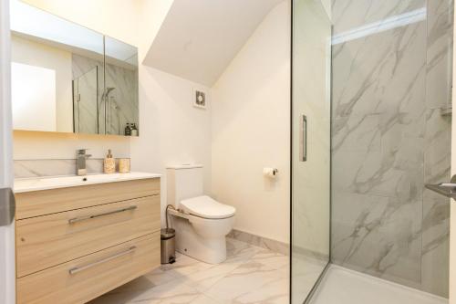 a bathroom with a toilet and a glass shower at Entertaining townhouse by Little High Eatery in Christchurch