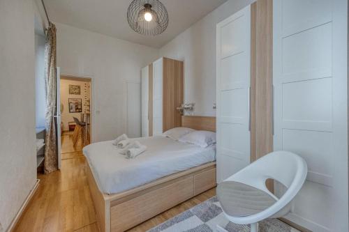 - une petite chambre avec un lit blanc et une chaise dans l'établissement Le Chaleureux - Verdun - Centre Ville, à Grenoble