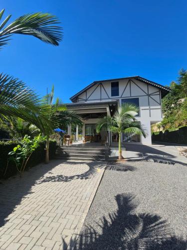 a building with palm trees in front of it at Pousada & Hospedagem Estação in Domingos Martins