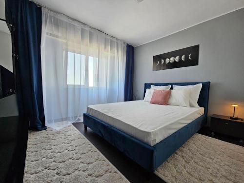 Un dormitorio con una cama con cabecero azul y una ventana. en Blue Marina Sea View, en Mangalia