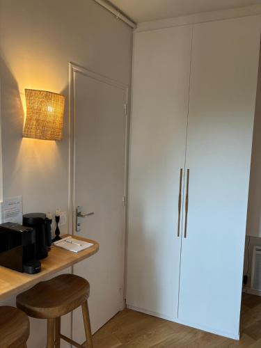 une armoire blanche dans une pièce avec un bureau et un tabouret dans l'établissement Studio cosy with incredible view, à Paris