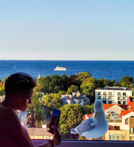 a man taking a picture of the ocean and a boat at Pokoje przy plaży z widokiem na morze in Sopot