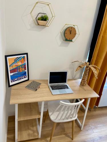 un ordinateur portable assis sur un bureau en bois avec une chaise dans l'établissement Les Halles studio unique et cosy, à Limoges