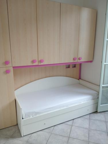 - un lit blanc dans un dortoir doté d'armoires en bois dans l'établissement Porta di mare studio, à Menton