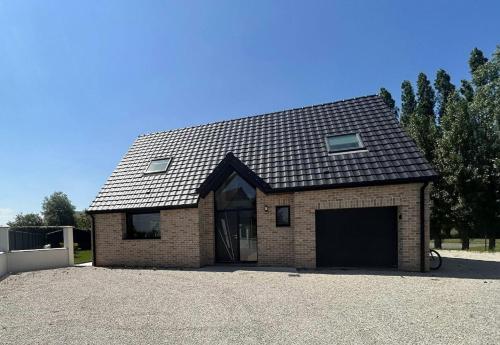 une maison en briques avec un grand garage dans une allée. dans l'établissement La prestigieuse, à Leffrinckoucke