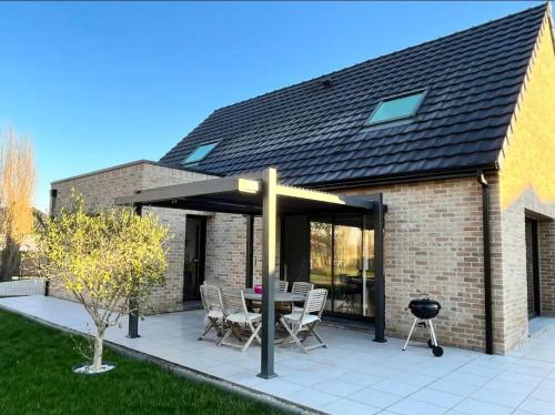 un patio avec une table, des chaises et un barbecue dans l'établissement La prestigieuse, à Leffrinckoucke