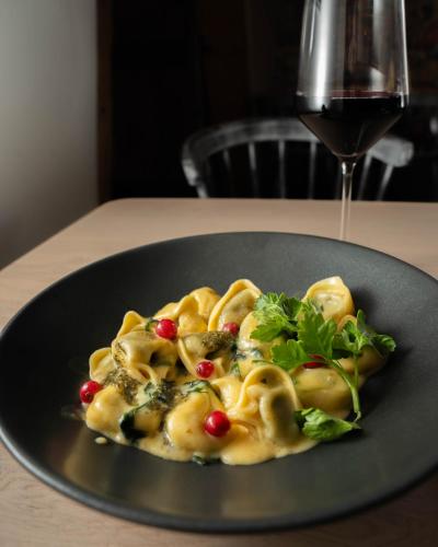 a plate of pasta with vegetables and a glass of wine at Hotel Restaurant Wolfsschlucht GmbH in Bad Münstereifel