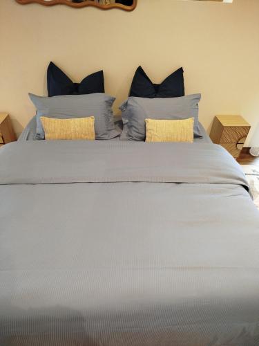 a large white bed with blue pillows on it at Grange du lac in Meillerie